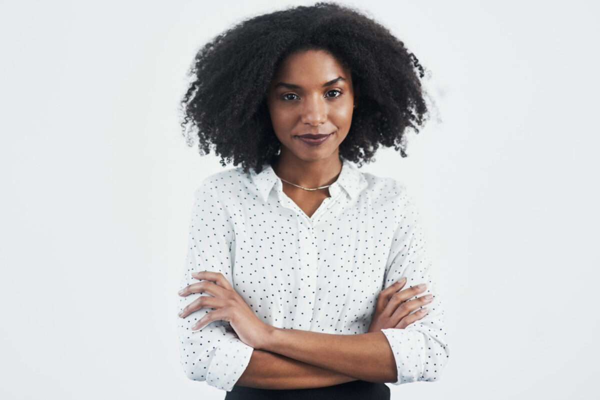 Studio shot of a confident young businesswoman against a gray background.
